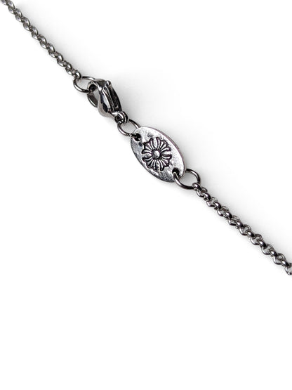 Detailed view of floral engraved oval tag and lobster clasp on silver layered necklace