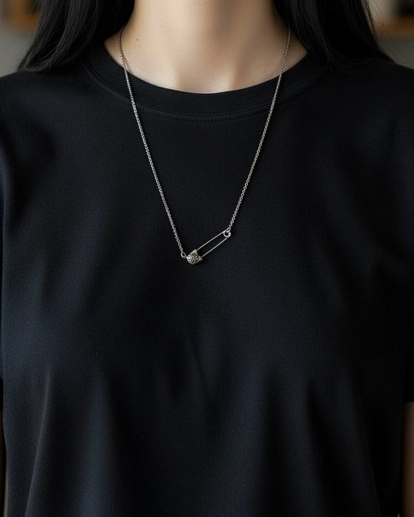 Woman wearing silver safety pin pendant necklace with daisy charm on layered stainless steel chains